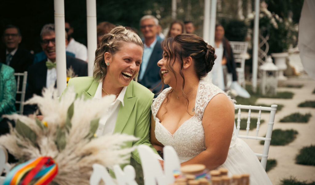 Due spose sorridenti che si guardano all’altare durante il loro matrimonio LGBTQ a Torino