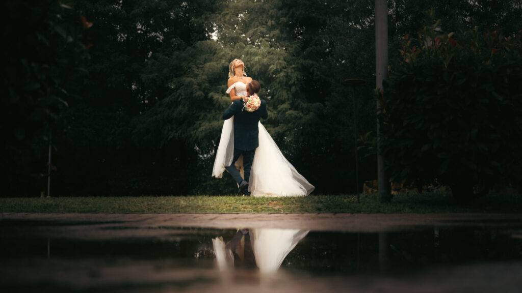 Sposo che tiene in braccio la sposa, sollevandola in un momento romantico durante il loro matrimonio
