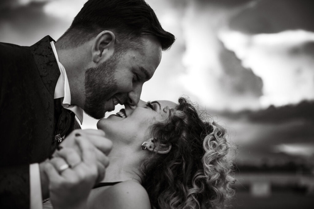 Coppia sorridente ripresa da vicino in bianco e nero dal basso, durante il loro matrimonio