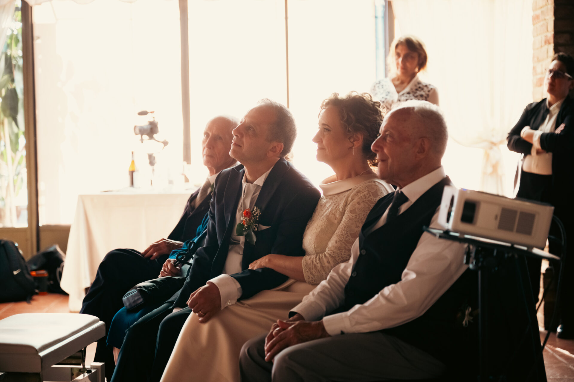 Wedding Video - Sposi insieme a parenti e amici emozionati mentre guardano la proiezione cinematografica live del matrimonio