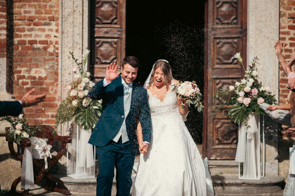 Sposi emozionati e sorridenti che salutano gli invitati appena usciti dalla chiesa, pieni di gioia