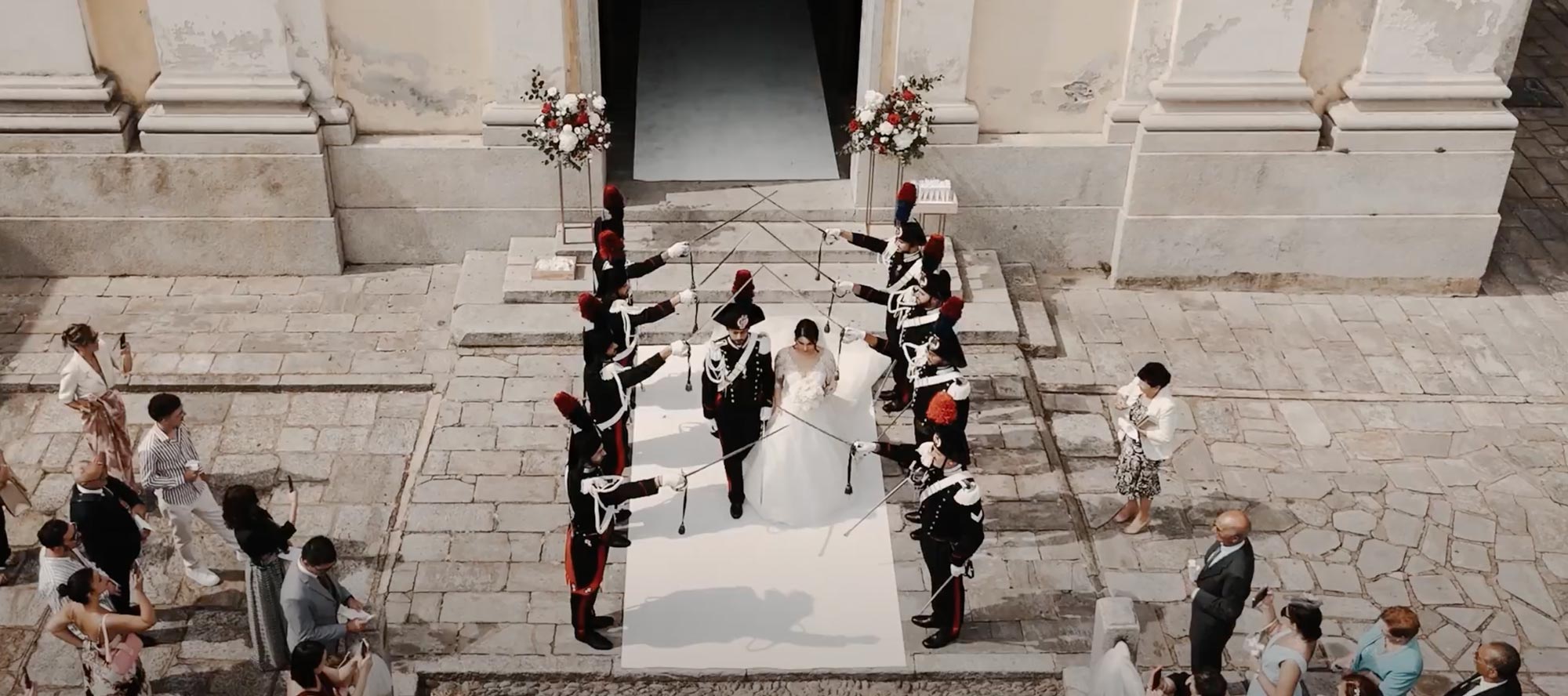 Wedding Video - Sposi che escono dalla chiesa sotto un arco di spade, in un matrimonio con carabiniere, ripresi dall’alto